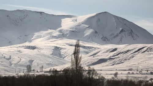 Snowy Mountain Ranges on Edge of Flat Terrain in Sunny Winter