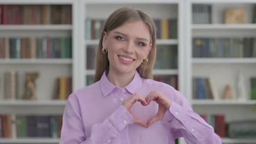 Woman Makes Heart with Hands and Smiles