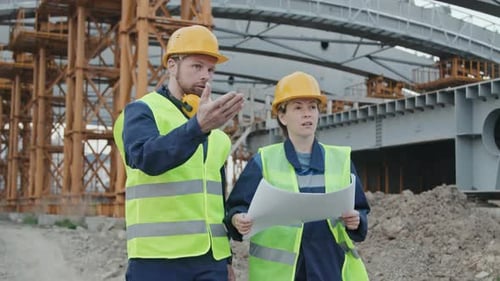 Construction Engineers Discussing Blueprint and Walking