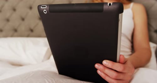 Woman using digital tablet on bed