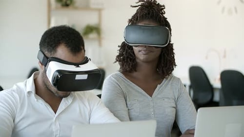 Aufgeregte Benutzer tragen VR-Headsets, während sie im Büro sitzen
