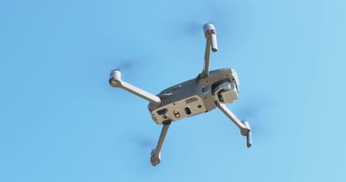 Unteransicht einer fliegenden Drohne ohne Bewegung vor blauem Himmel in sonnigen Wettersensoren und einem