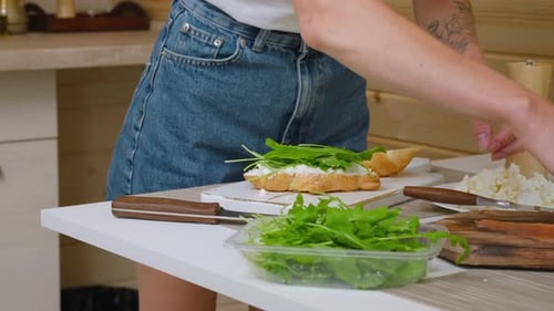 Woman Prepares Salmon Croissant Sandwich in Kitchen