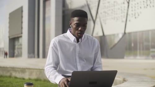 Adult Video Conferencing on Laptop Outside Office Building