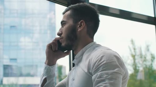Man Talking on Phone by City Window