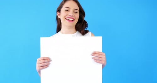 Beautiful woman holding blank placard on blue background
