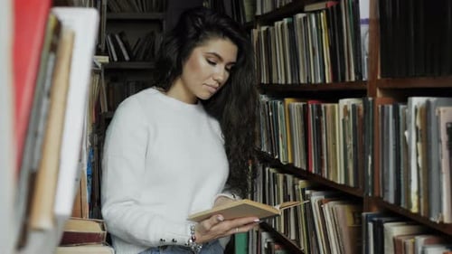 Young Woman Reading a Book in the Old Library Closeup