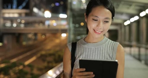 Woman Uses Tablet in City at Night