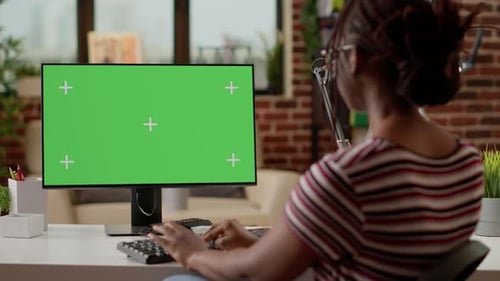 Freelancerin schaut mit Greenscreen auf Computer