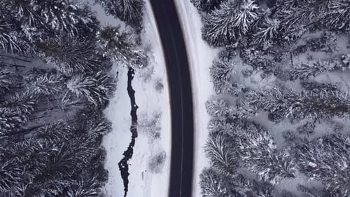 Vista aérea desde arriba, bosques nevados, montañas, con automóviles conduciendo por la carretera de invierno.