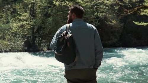 Der Mensch beobachtet die Natur im Wald, steht mit dem Rücken zur Kamera und mit dem Gesicht zum Fluss