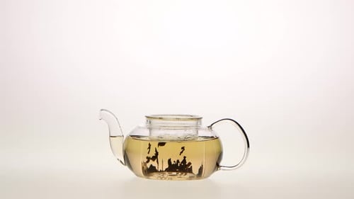 Leaves of Green Tea Are Brewed in Teapot, White Background