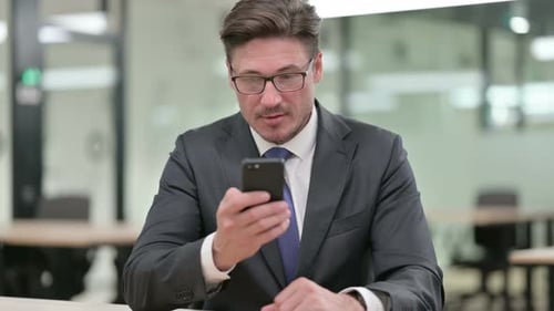 Adult Man Uses Smartphone in Modern Office