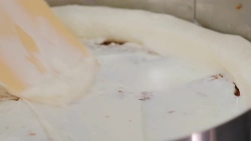 Nahaufnahme des Kochs, der mit einem Metallspatel Sahne auf den Kuchen aufträgt