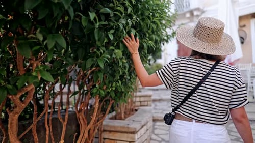 Back View of Traveling Woman in Straw Hat Exploring Ancient City in Greece or Italy