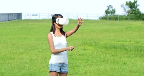 Woman watching with virtual reality device and sitting at the park