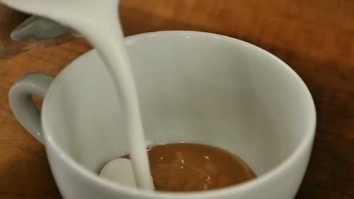 Verter la leche del chorro en una taza de café