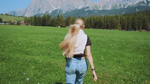 Back View of Woman Running on the Field with Mountains in Front