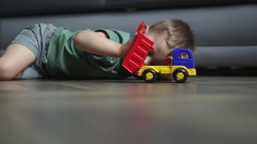 Young Child Playing With Toy Dump Truck at Home