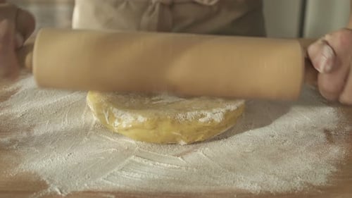 Adult Rolling Dough on Wooden Board in Kitchen