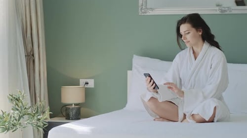 Woman Using Mobile Phone Sitting on Bed
