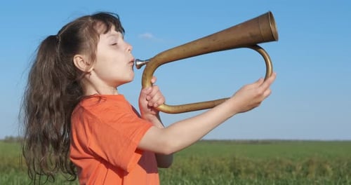 Girl Plays Bugle in Sunny Green Field