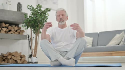 Senior Man Meditating in Bright Living Room