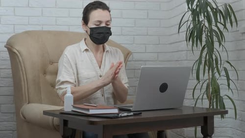Woman Applying Hand Sanitizer Then Using Laptop