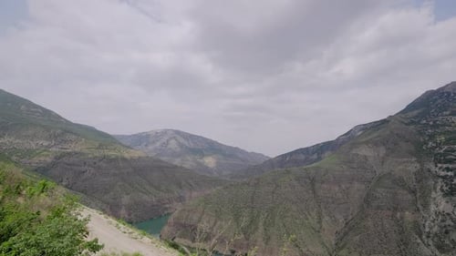 River in rocky mountains on background of cloudy sky