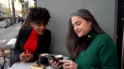 Women Enjoying Coffee and Phones at Outdoor Cafe