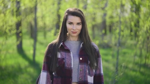 Portrait of a Young Brunette on a Background of Green Trees