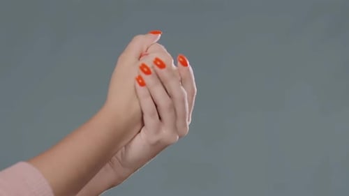 Une jeune femme se frotte les mains avec une manucure rouge et désinfecte