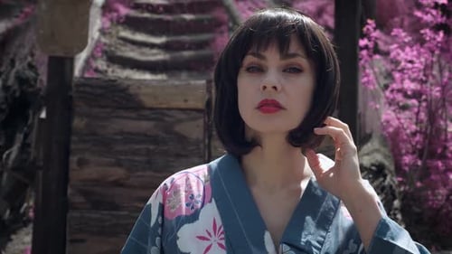 Steadicam-Aufnahme einer schönen kaukasischen Frau, die wie eine japanische Geisha gekleidet ist und draußen auf Sakura steht