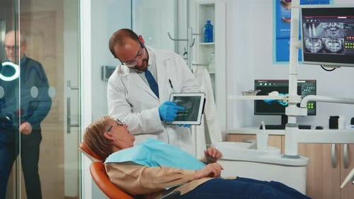 Estomatólogo que revisa la radiografía del diente con un paciente mayor