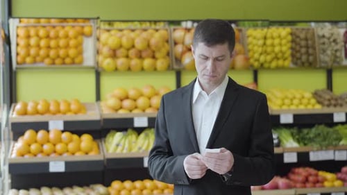 Front View of Adult Caucasian Man Checking Bill in Grocery with Surprised Facial Expression