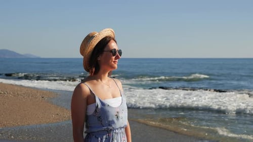 Woman Standing on a Sunny Beach Staring at Ocean