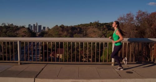 Woman Jogging on Sidewalk Near City Buildings