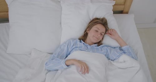 Happy Beautiful Woman Wake Up, Smiling and Stretching Her Arms in Her Bed in the Bedroom. Young