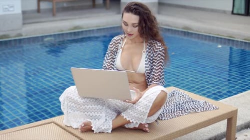 Woman Uses Laptop Computer Poolside at Tropical Resort