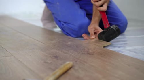 Man Installing Laminate Wood Flooring in Home