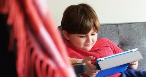 Boy Playing Tablet Device on the Couch