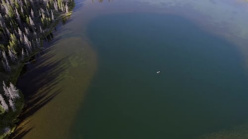 Aerial view flying down towards person kayaking in lake