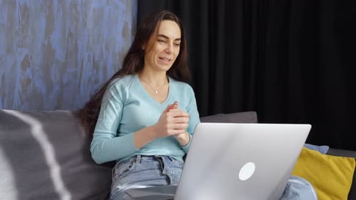Woman Video Calling Using Laptop on Couch at Home