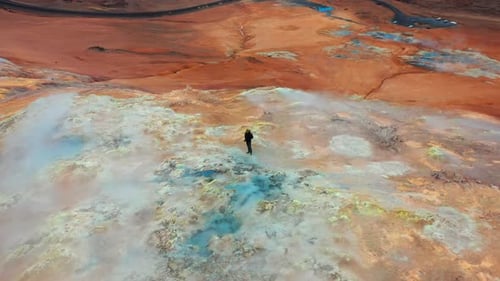 Man Exploring Geothermal Landscape with Steaming Vents
