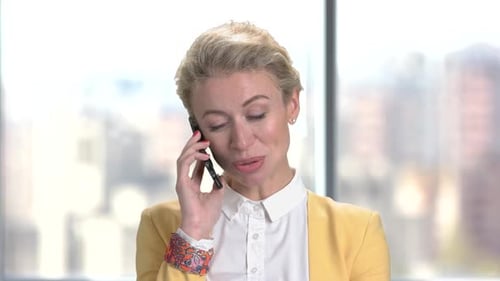 Blonde woman talking on cell phone at work