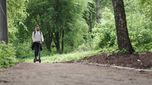 Der Typ fährt einen Elektroroller im Sommerwald