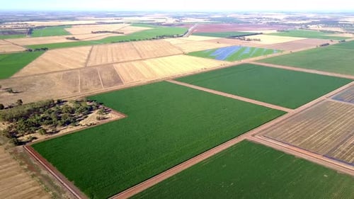 Panoramic aerial view over a vast, flat area of rural land. Different shades of green and brown illu