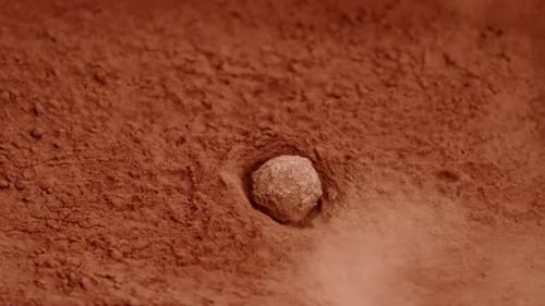 Rock Falling onto Surface of Red Clay