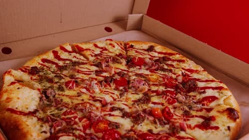 Close up of large pizza in box on red background.
