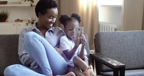 Woman and Child Using Cellphone Together on Couch